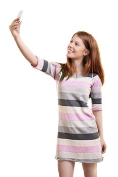 Beautiful smiling fashionable young woman in a casual dress taking a selfie with a smartphone, isolated on a white background. Full body length portrait, isolated on white background.