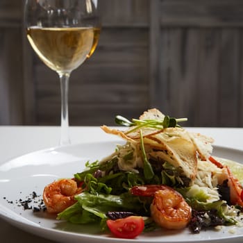 Fresh caesar salad on white bowl with parmesan cheese and shrimps