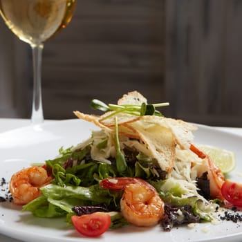 Fresh caesar salad on white bowl with parmesan cheese and shrimps