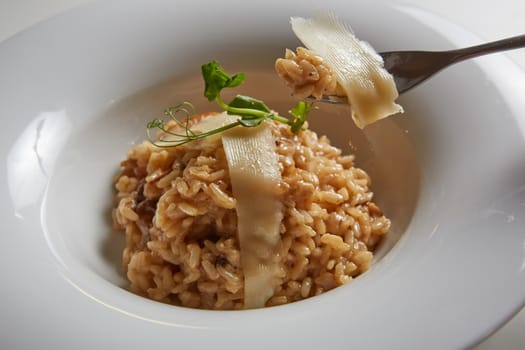 Italian dish risotto with wild white mushrooms and Parmesan cheese in a white plate