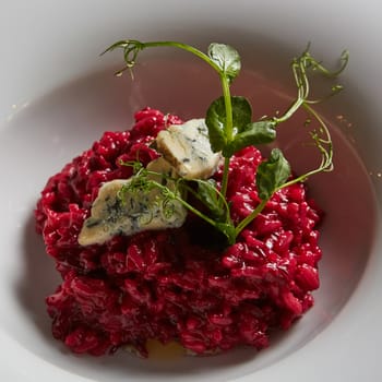 Beetroot risotto with blue cheese on a white plate