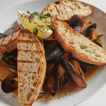 Seafood. Mussels in wine with croutons and lemon. Clams in the shells. Delicious snack for gourmands. Selective focus