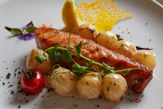 Roast salmon with potatoes on white plate. Shallow dof.