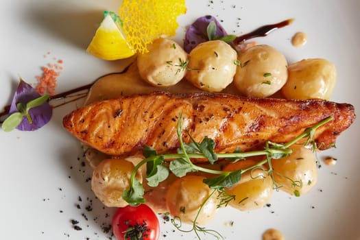 Roast salmon with potatoes on white plate. Shallow dof.