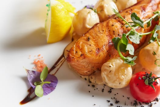 Roast salmon with potatoes on white plate. Shallow dof.