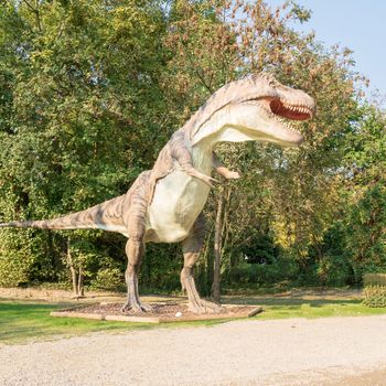 Big model of prehistoric dinosaur like tyrannosaurus rex  in nature. Realistic scenery.sunny day.