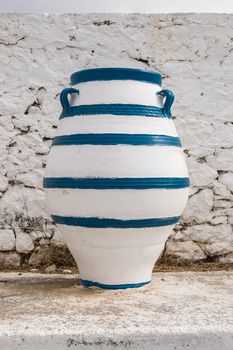 Old blue and white amphora lay on the ground in front of a white wall on the island of Crete