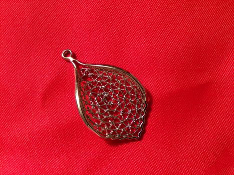 Beautiful pendant on red silk fabric. Pendant made of silver in the form of a tree leaf.