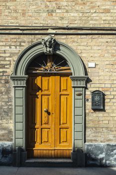 Old typical italian wooden door. Italian house. Ancient house facade. Sunlight. Round door arch. Stone build house. Wrought iron door handles.