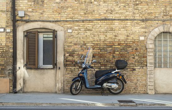 Typical italian motorbike in front of old house facade. Traditional bike and ancient mediterranean architecture.