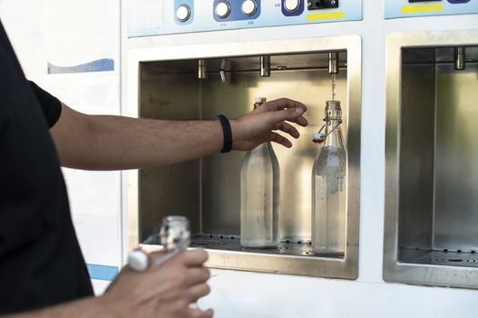 Mineral Water machine on the street. Filling mineral water bottles from a water dispenser. Pay and load drinking water.