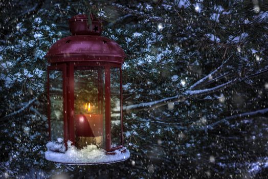 Christmas lamp with glass and candle inside in the night to pine tree. Snowing around the lamp. Snowflakes flying in the night.