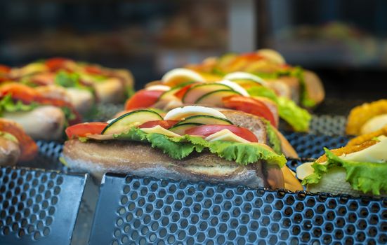 Sandwich on shelf in bar. Showcase light. Fast food with bread meat and vegetables.