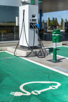 Electric charge station. Electric plug for charging cars. Car charging symbol painted on asphalt. Ecology fuell concept.