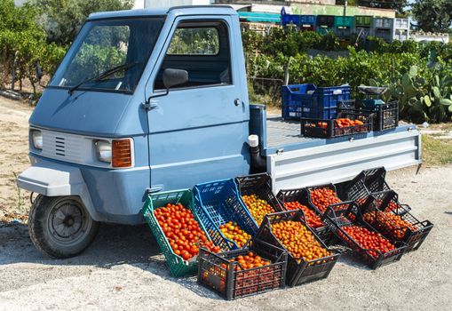 Small italian apo truck with tomatoes. Street market. Farmer sale tomatoes on the street in Italy.