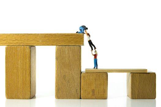 minitature figures man helping woman climbing up and coming higher