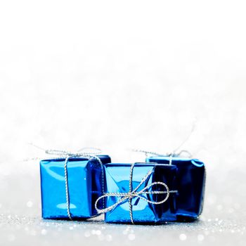 Blue holiday gifts on silver glitter background