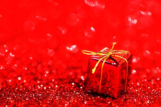 Decorative red box with holiday gift on shiny glitter background