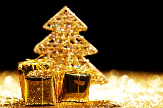 Beautiful golden decorative christmas tree and gifts on golden glitter background