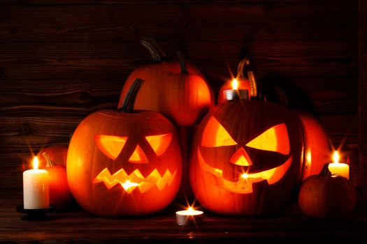 Group of Halloween pumpkin head jack o lantern and candles on dark wooden background