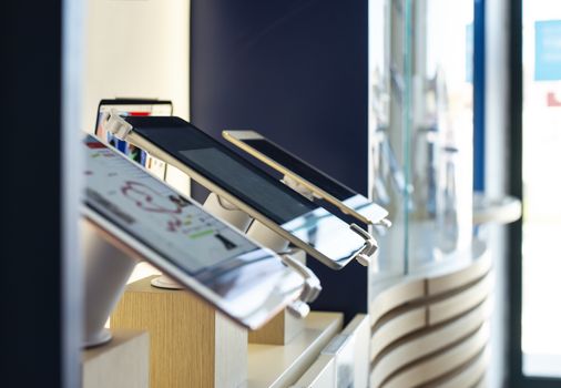 Cell Phones on shelf in telecommunication shop. Lights over GSM phones. Showcase in store for technology devices. Concept for communication and data.