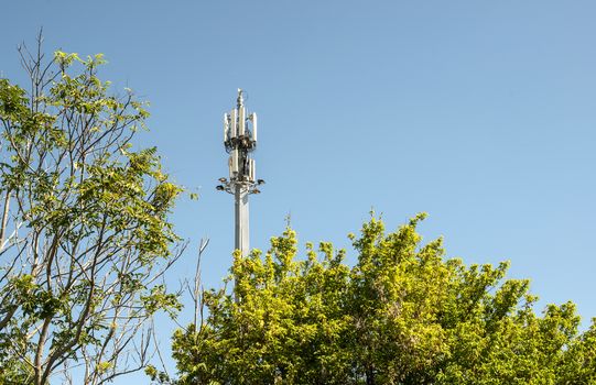 5G antenna outside the city. GSM Antenna in the nature. New 5G technology for internet concept. New Transmitter tower and trees.