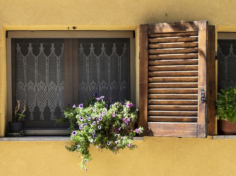 Typical italian facade with window. Italian house. Traditional style and ornaments. Flowers on the window.