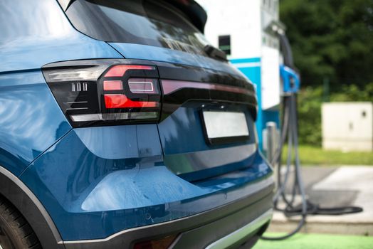 Electric car on gas station. Blue car and electric plug for charging. Ecology green fuels concept.