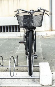 Black bike mounted on a bicycle stand on italian street. 
