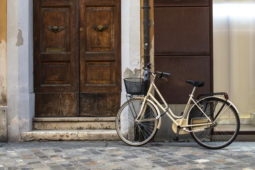 Beige bike with basket on italian street. Typical italian architecture on background. Sunny day. Typical italian style.
