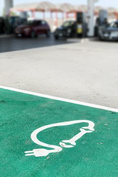 Electric charge station. Car charging symbol painted on asphalt and many cars on the background. Ecology fuell concept.