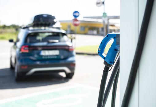 Electric car on gas station. Blue car and electric plug for charging. Ecology green fuels concept.