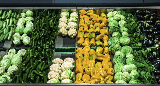 Vegetables on shelf in supermarket. Cabbage, zucchini, pepper and cauliflower.