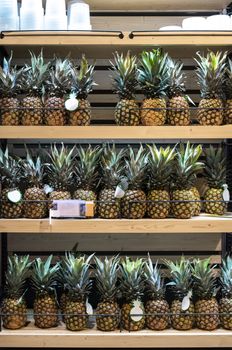 Ananas on shelf in supermarket. Many ananases in shop.