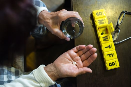 Senior woman take pills from box. Healthcare and old age concept with medicines. Medicaments on table.