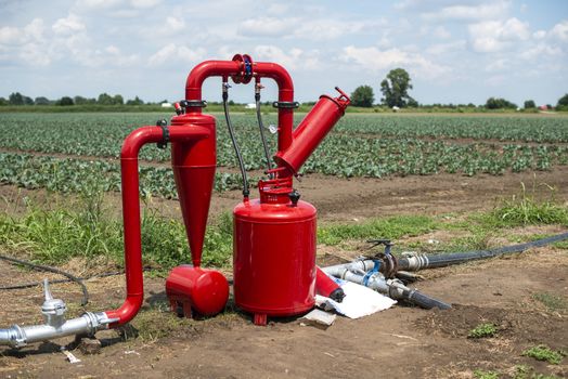 Water pump and pipes on farmland. Agriculture and watering concept.