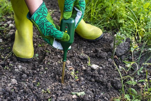 Nutrients soil meter. Measure soil for nitrogen content with digital device. Woman farmer in a garden. Concept for new technology in the agriculture.