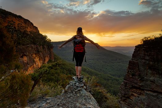 Adventurous hiker standing firm on the narrow cliff ledge of the mountain gully looking out to distant views of further mountain escarpment as the sun sets in the late afternoon
adventure
carefree