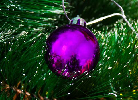 Christmas toy ball lies on the needles of an artificial Christmas tree. Christmas ball on artificial Christmas tree.