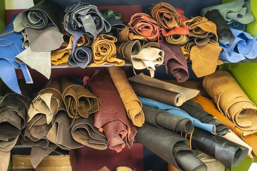 Many rolls leather on shelf in leather workshop.