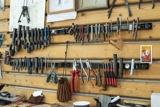 Hammer on shelf and leather in workshop.