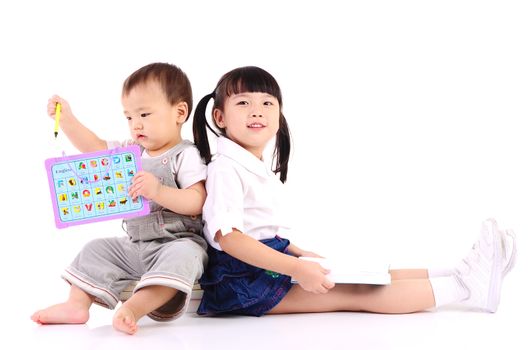 Asian kids sitting on the floor,reading book and playing with toy