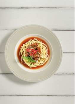 Top view spaghetti with sardines fish in tomato sauce on dish over wooden background