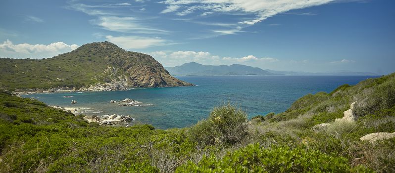 Wide wiew of a Panorama of a natural bay in the south of Sardinia in Italy with the mountains overlooking the sea in broad daylight during the summer.