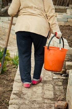 Farmer woman carrying an orange bucket walking outdoor