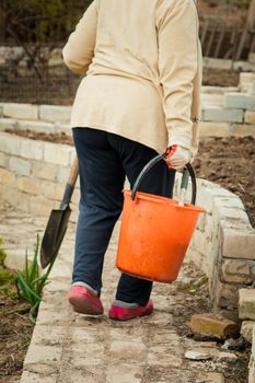 Farmer woman carrying an orange bucket walking outdoor