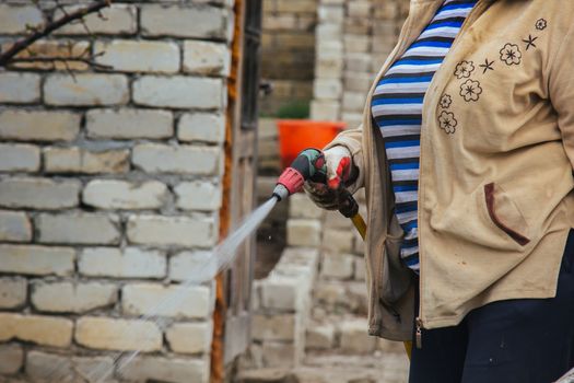 gardening and people concept - happy senior woman watering lawn by garden hose with sprayer at autumn