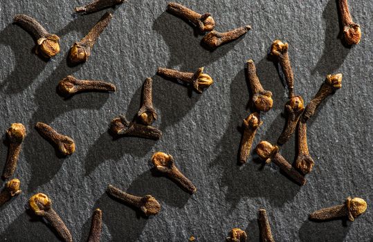 Dried Cloves on dark stone background. Natural hard light. Spice cloves close-up shot. Cooking with aromatic condiments conceptual background.