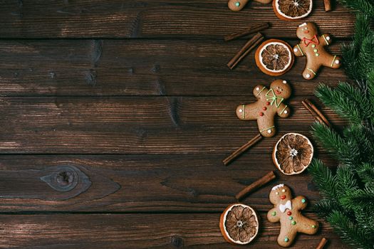 Christmas flat lay background with traditional gingerbread cookies dried orange cinnamon and fir tree on wood
