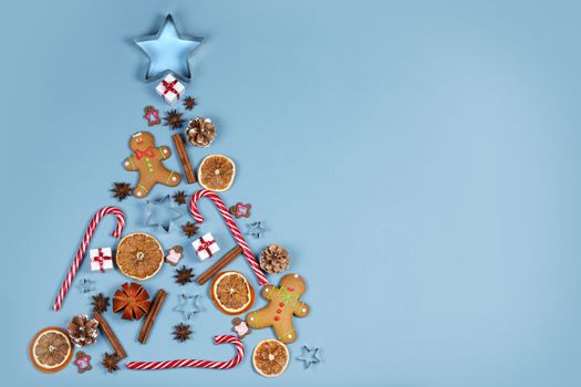 Christmas tree symbol composition. Ginger cookies caramel candy canes mold star form gifts orange and baubles, flat lay with copy space